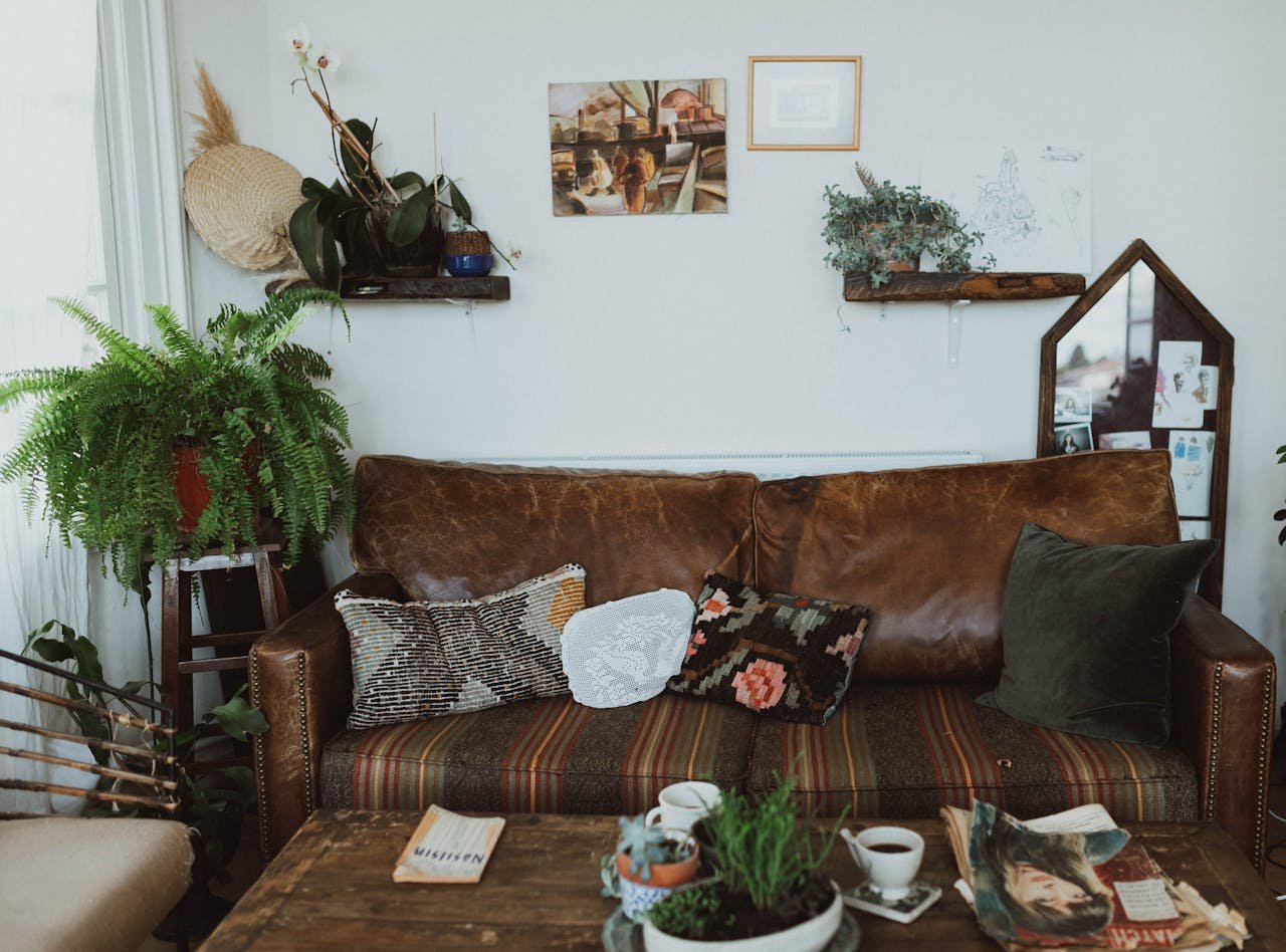 A cozy living room with a leather sofa, plants, and a rustic table creating a warm and inviting space.