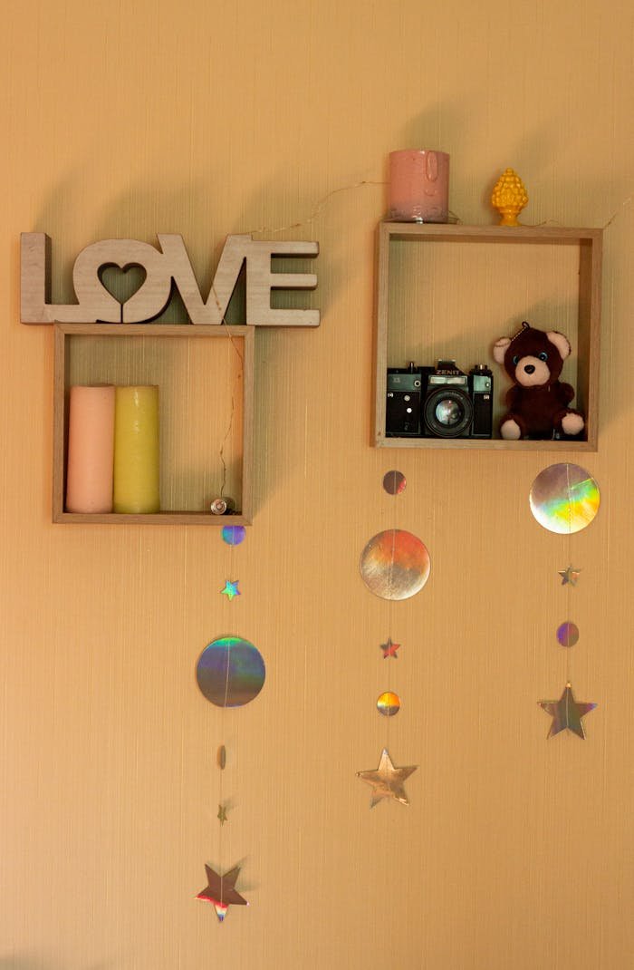 Cozy shelf decor featuring a wooden love sign, vintage camera, teddy bear, and star hangings.