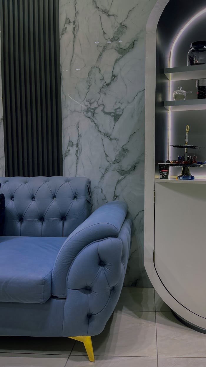 Stylish living room with a blue tufted sofa and modern marble wall backdrop.